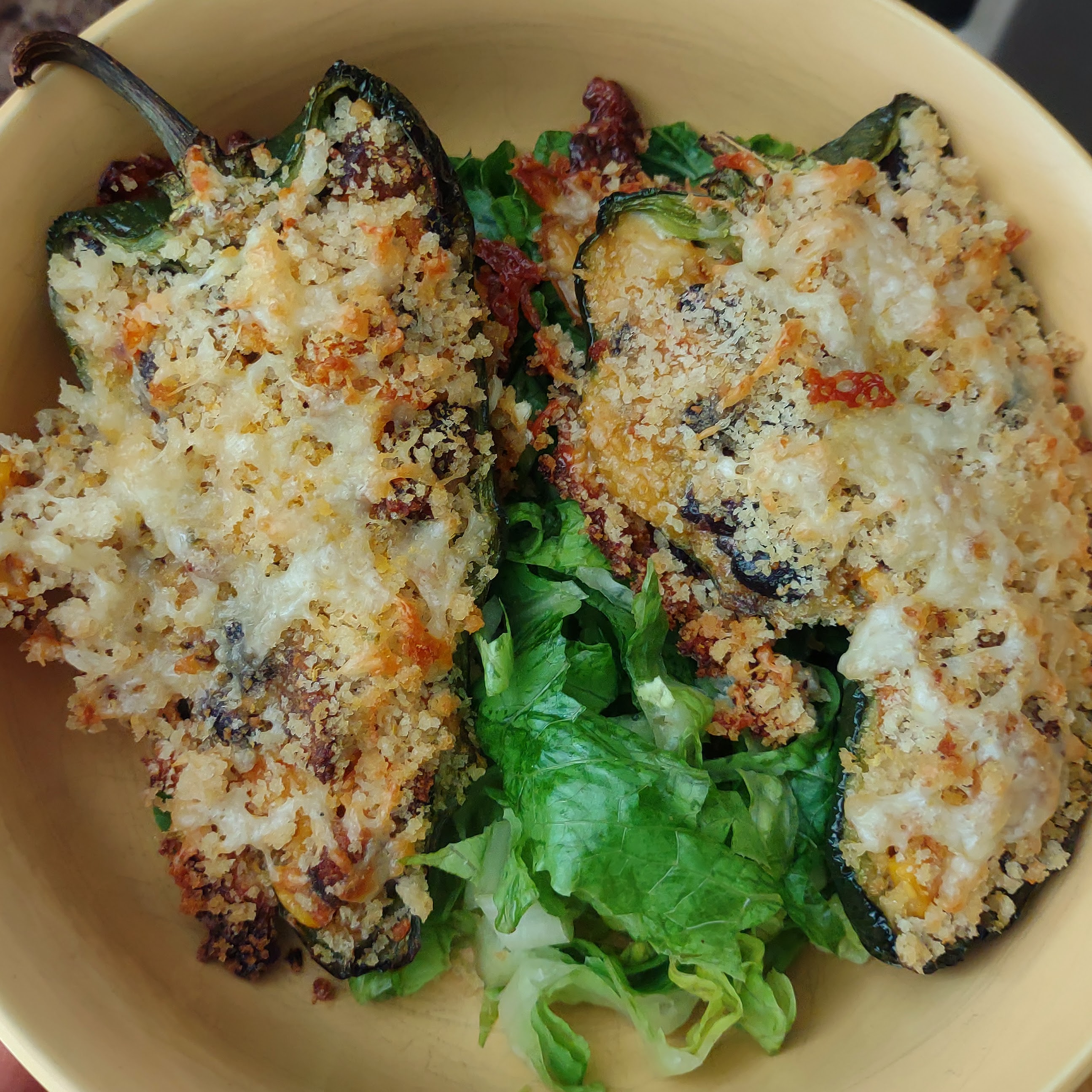 Two stuffed poblano peppers on a plate.